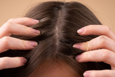 Center part showing brown hair with visible scalp; hands parting hair to highlight thinning