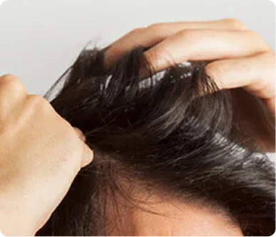 Hands massaging the scalp through dark hair, demonstrating a gentle scalp-massage step in a hair treatment routine