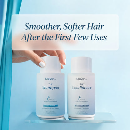 Two white bottles of Kigourist hair care products, labeled 'The Shampoo' and 'The Conditioner', displayed on a clear acrylic shelf with a hand reaching toward the shampoo bottle. A text overlay at the top reads, 'Smoother, Softer Hair After the First Few Uses' against a light blue background.